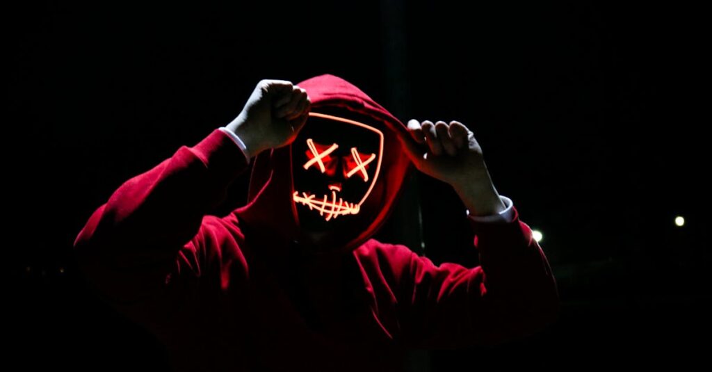 Aktualny obrazek: A spooky illuminated mask figure with a red hoodie in a dark setting, perfect for Halloween themes.