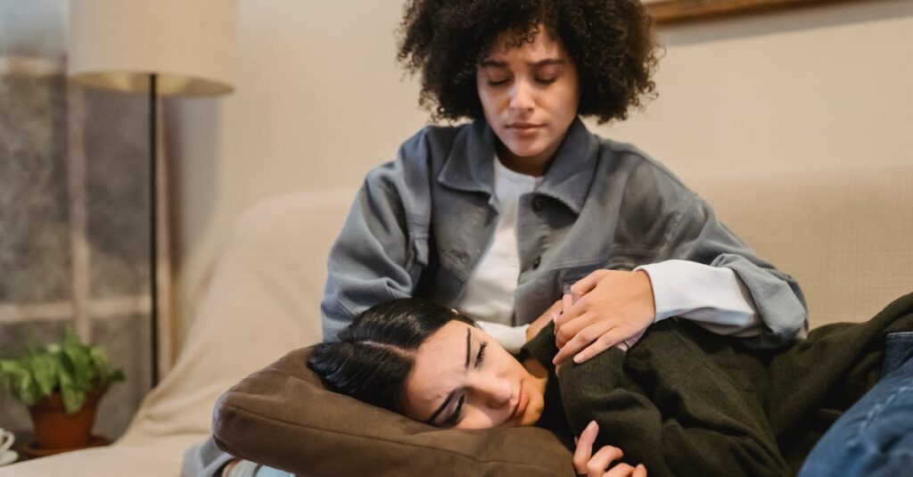 Two women share a comforting embrace in a living room, displaying support and friendship.